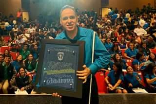 La foto muestra a Manolo posando junto a estudiantes de la Sociedad de Honor del Colegio Maristas en Guaynabo.